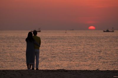 Couple overlooking calm sea at sunset