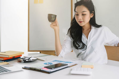 Young woman using phone while sitting on table