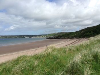 Scenic view of beach against cloudy sky