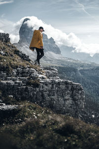 Man standing in the dolomites with a view of the mountain tops of tre cime in italy