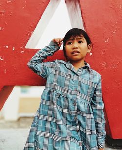 Portrait of boy standing against red wall