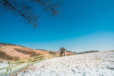 Scenic view of snow covered land against clear blue sky