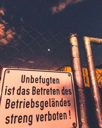 Low angle view of information sign on metal at night