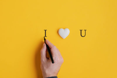 Close-up of person hand against yellow wall