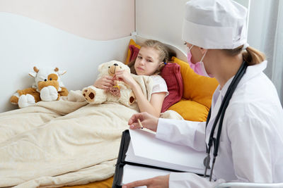 Rear view of girl with toy on bed