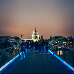 People in illuminated city against clear sky at night