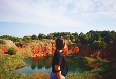 Side view of young woman standing on mountain against sky during sunny day