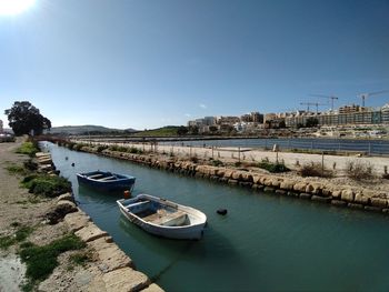 Sailboats moored on river against clear blue sky