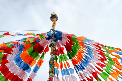 Low angle view of multi colored flags hanging against sky