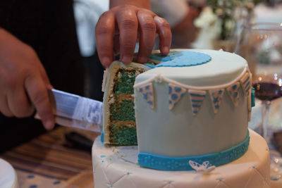 Cropped hand of child cutting birthday cake