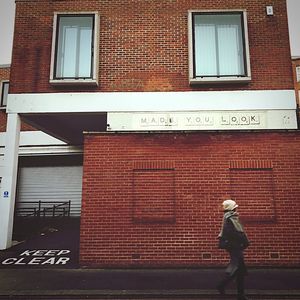 Full length of man standing against brick wall