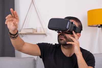 Young man in vr glasses headset at home interacting with virtual reality, gesturing.  video gaming