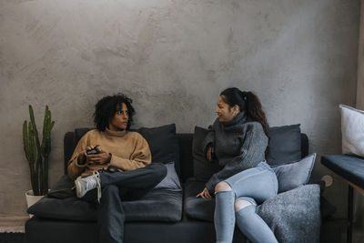 Businesswoman discussing with female colleague sitting on sofa in startup company