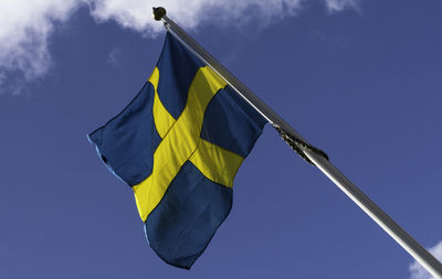 Low angle view of flag against blue sky