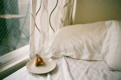 Food on plate in bed next to window