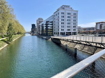 Bridge over river by buildings in city against sky