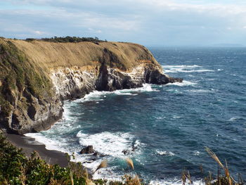 Scenic view of sea by cliff against sky