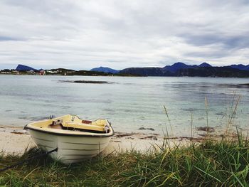 Boats moored at lakeshore against sky