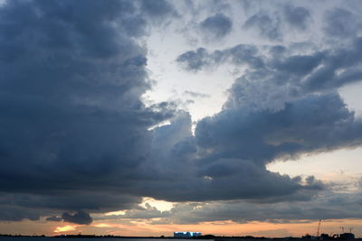 Low angle view of sunlight streaming through clouds during sunset