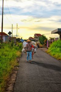 Rear view of people walking on road against sky