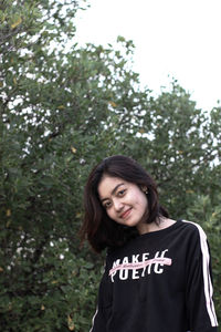 Portrait of a smiling young woman against trees