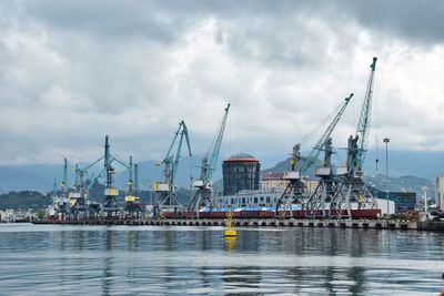 Cranes at commercial dock against sky