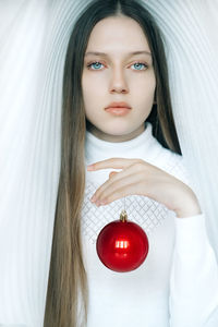 Girl with expressive eyes in a snow-white dome with a bright red christmas ball