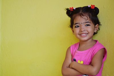 Portrait of smiling girl against yellow wall