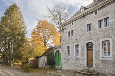 Trees by building against sky