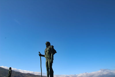 Low angle view of man standing against clear blue sky