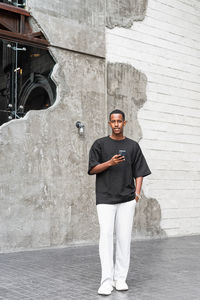 Portrait of young man standing against wall