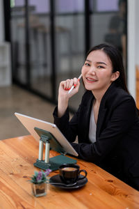 Portrait of a smiling young woman sitting at table