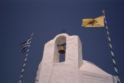 Low angle view of greek flag and bell tower against clear sky