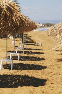 Close-up of thatched roof umbrellas at beach against sky