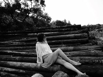 Woman relaxing on pile of wooden logs