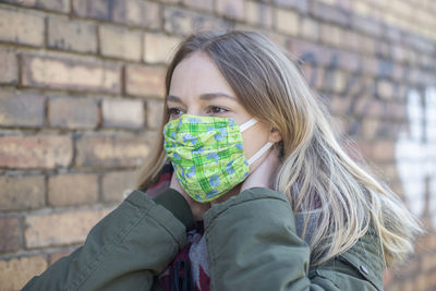 Portrait of woman wearing mask against wall