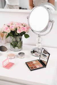 Cosmetics for make-up, round mirror and roses flowers on table. decorative cosmetics, brushes, eyes