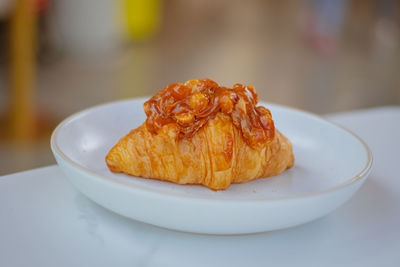 Croissant with macadamia nuts topping, homemade with white table background.