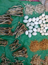 High angle view of dried fish and eggs on plastic at market for sale