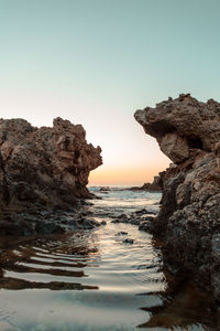 Scenic view of rock formation in sea against clear sky