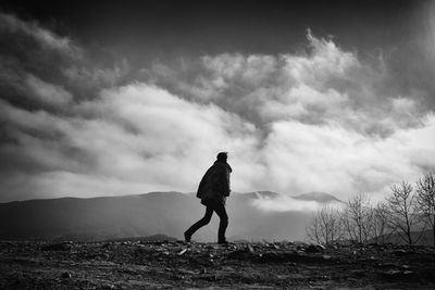 Rear view of man standing against cloudy sky