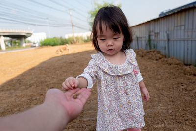 Baby girl giving stone to person on field