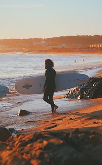 Man standing on beach against sky during sunset