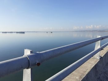 Close-up of railing by sea against blue sky