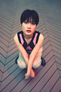 Portrait of young woman sitting on hardwood floor
