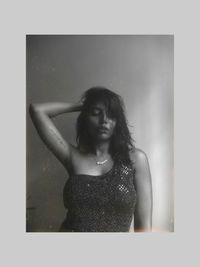 Young woman looking away while standing against white background