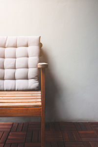 Wooden armchair on wood floor, grey wall background, terrace with warm sunlight.