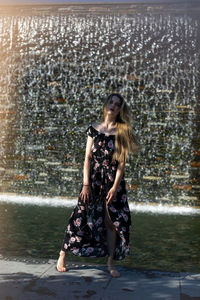 Full length portrait of woman standing against water