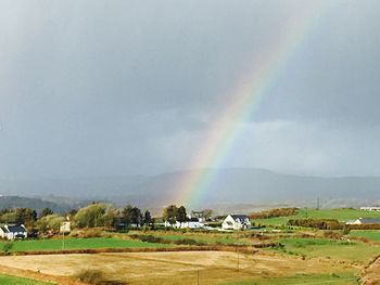 Scenic view of rainbow over field against sky