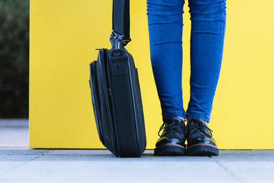 Low section of person with bag standing on footpath